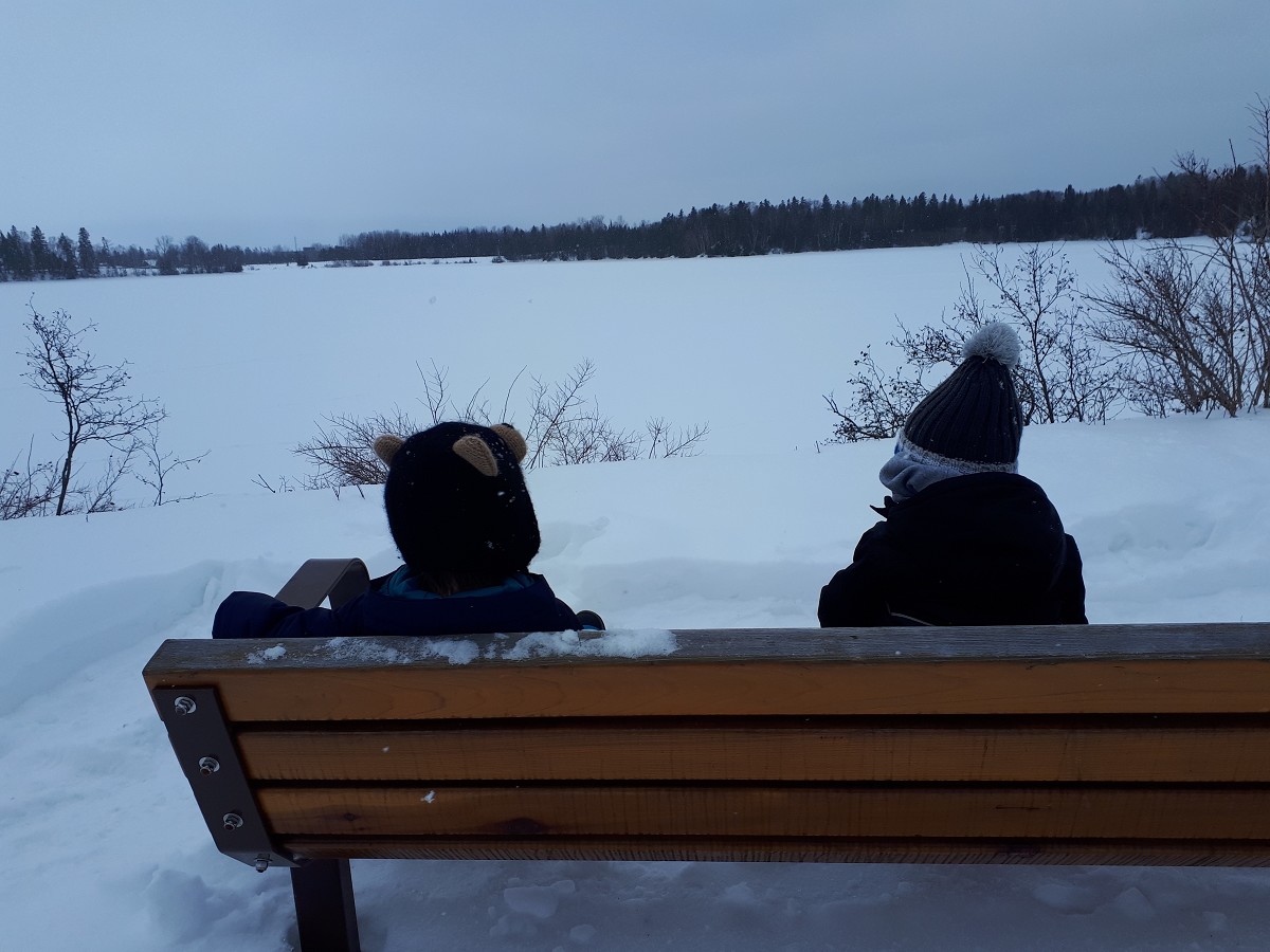 kids are sitting on a bench in the winter