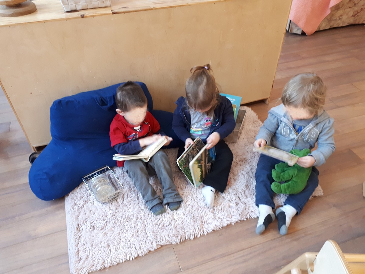 group of preschool kids reading books on the carpet